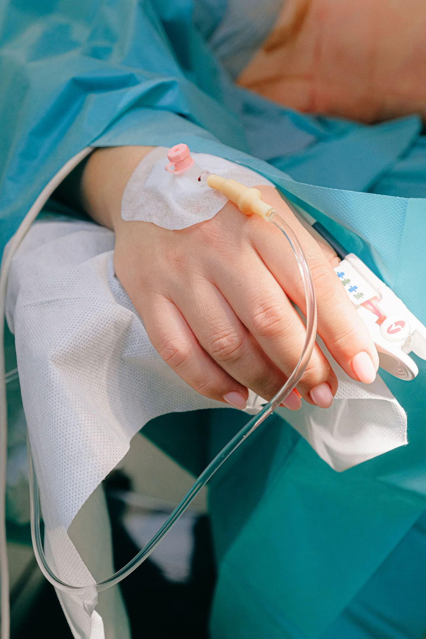 สายให้สารทางหลอดเลือดที่ยึดไว้บนมือผู้ใหญ่ เป็นภาพประกอบการดูแล IV