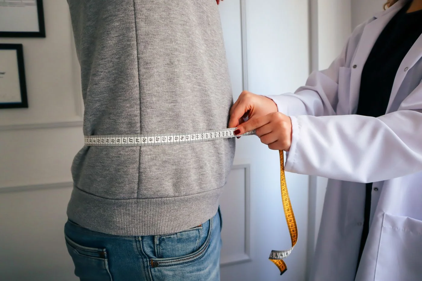 A waist measurement during an assessment, with faces outside the frame